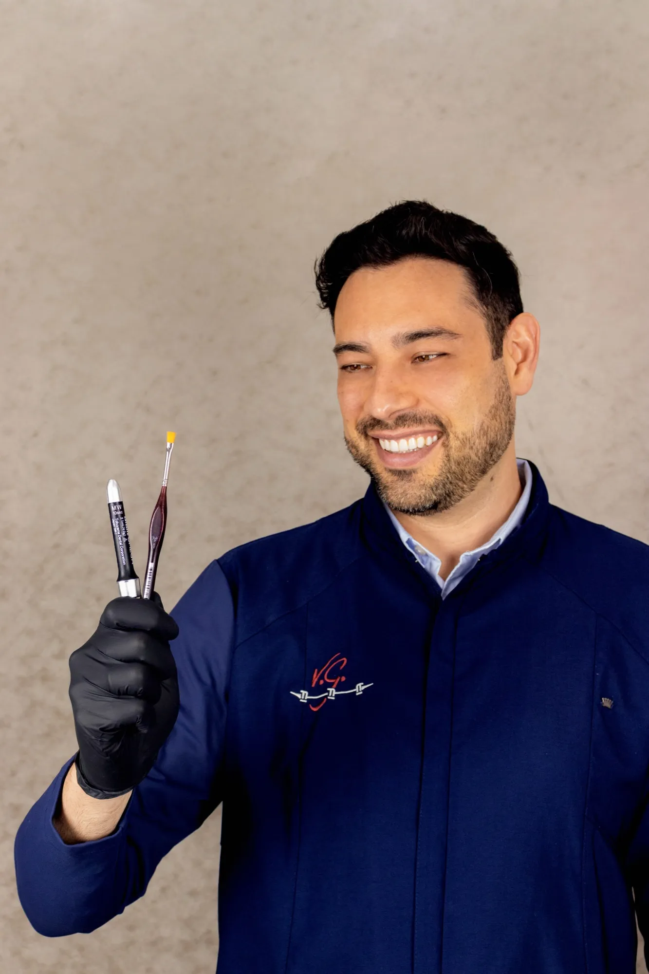 Dr. Thiago Majolo Valeretto, cirurgião-dentista, sorrindo e segurando instrumentos odontológicos